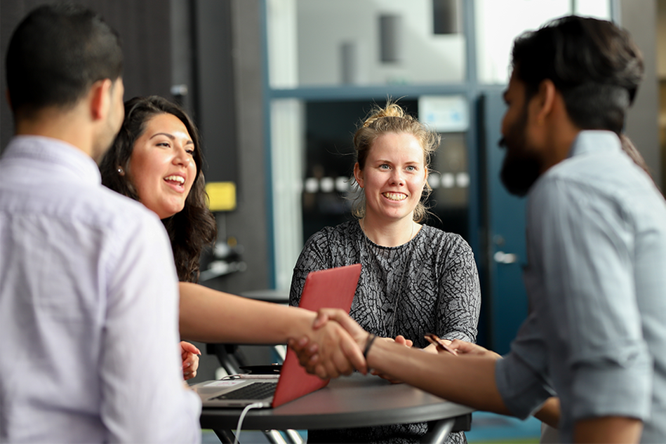 A woman and a man shaking hands, smiling. Photo.